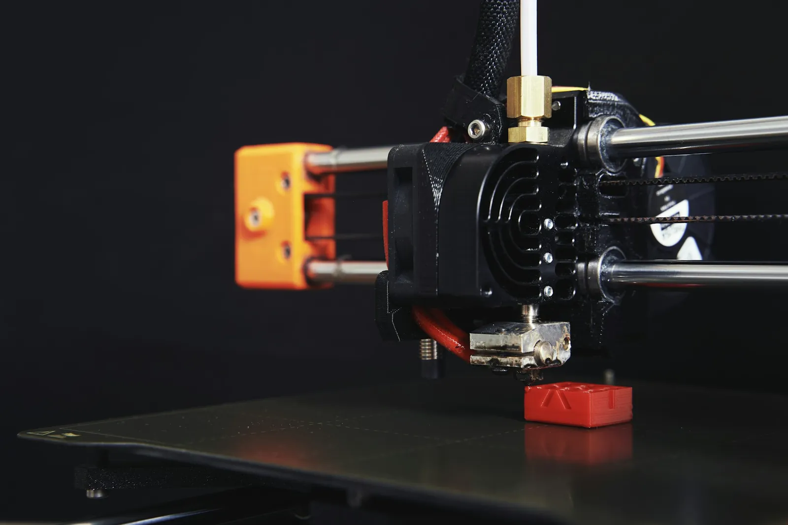 Cabeçote de uma impressora 3D imprimindo uma peça vermelha